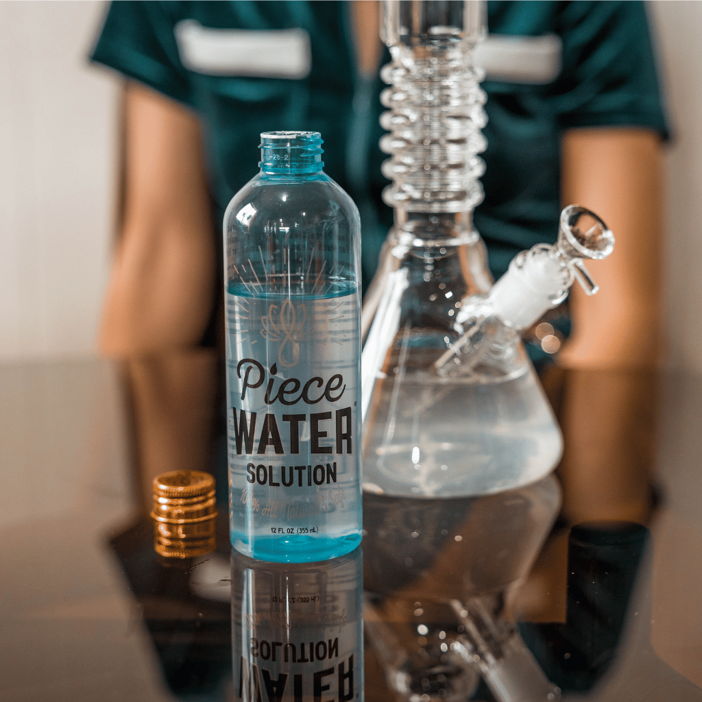 A bottle of Piece Water Solution next to a bong