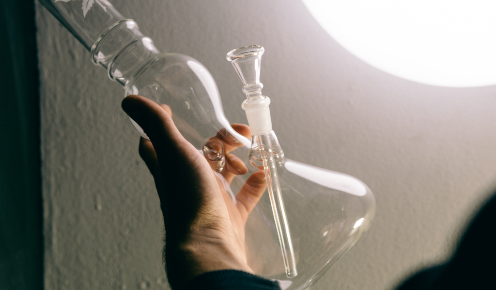 A hand holding an empty glass bong