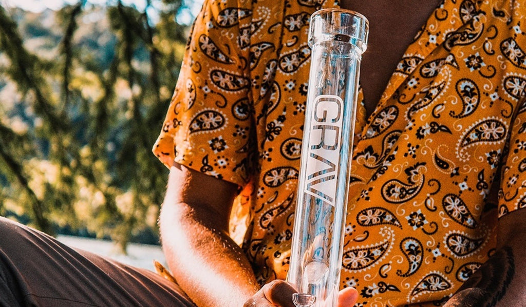 A man holding a straight tube bong