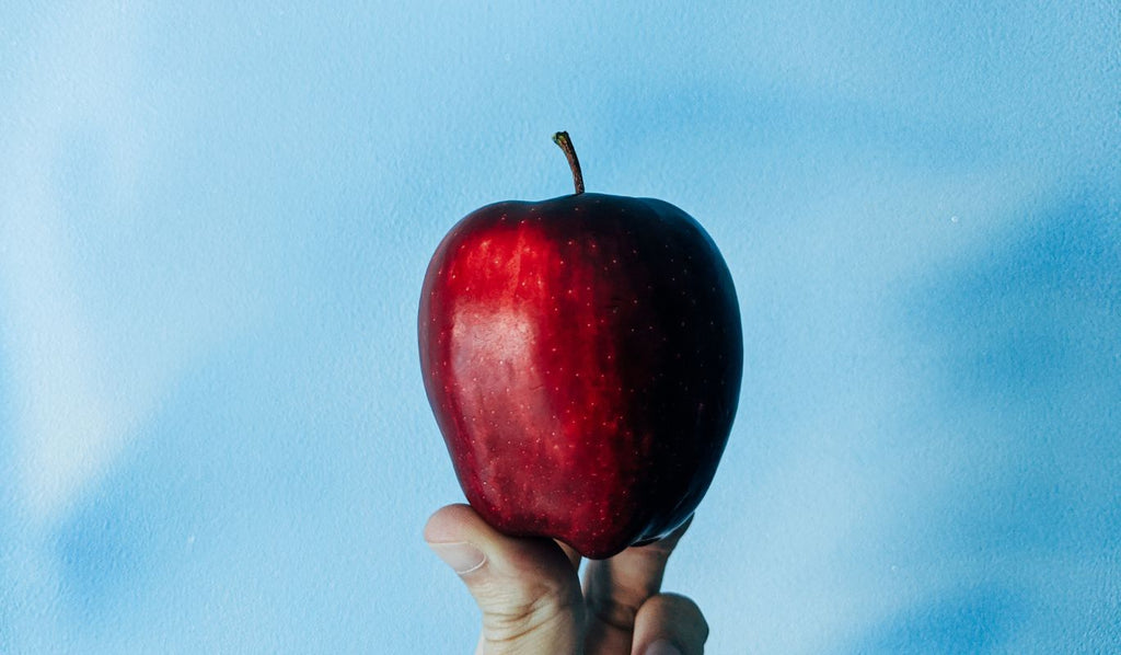 Fingers holding a red apple